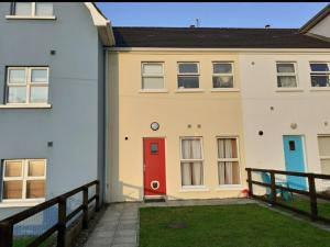 a white house with a red door on it at Beachside Holiday Home in Portrush