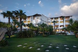 un gran edificio blanco con palmeras en un parque en Hotel Villa Margherita en Golfo Aranci