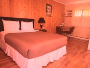 a bedroom with a large bed and a desk with a table at Wildwood Motel in Shelburne