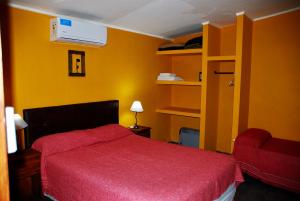 1 dormitorio con cama roja y pared amarilla en La Aldea en San Rafael
