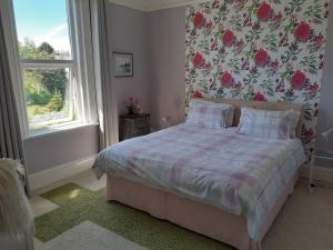 a bedroom with a bed with a floral wallpaper at Grantham House in Ryde
