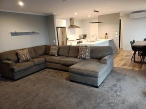 sala de estar con sofá marrón y cocina en Richmond, Nelson 3brm New Home en Richmond