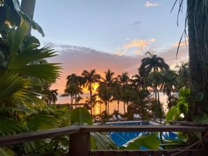a sunset view from the deck of a resort with palm trees at Villa Caribe in Lívingston