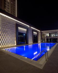 a large swimming pool with blue water at night at Sheraton Apartments in Bishkek