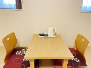 a table with a coffee maker and two chairs at Smile Hotel Kitaasaka in Asaka