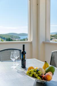 a plate of fruit on a table with a bottle of wine at Mladinic Palace in Milna