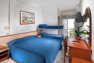 una camera ospedaliera con un letto blu e una scrivania di Hotel Holiday a Misano Adriatico