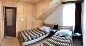 2 letti in una camera con pareti in legno e finestra di Guest House Gordila a Omalo