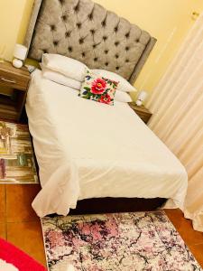 a bedroom with a large white bed with a flower pillow at Birds Paradise in Durban