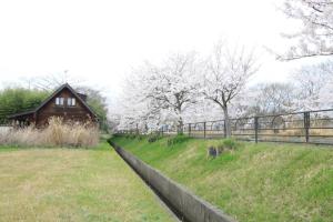 un campo con una valla, un granero y árboles en 風車村3-G-1B号棟 en Aiba