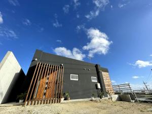 un edificio negro con una puerta de madera en City View GOAT, en Ishigaki Island