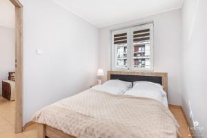 コウォブジェクにあるJantar Apartamenty - Osiedle Burtszynowe 1の白いベッドルーム(ベッド1台、窓付)