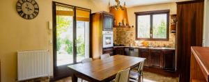 a kitchen with a wooden table and a clock on the wall at Le Raïs chez Anne Ravanat in Noyarey