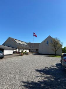 un bâtiment avec drapeau au milieu d'une allée dans l'établissement Blokhus-Hune Hotel og Vandrerhjem, à Blokhus