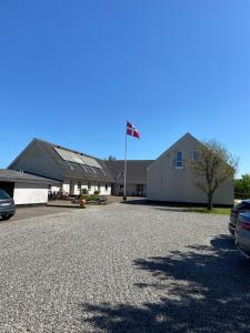 a building with a flag in the middle of a driveway at Blokhus-Hune Hotel og Vandrerhjem in Blokhus
