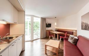 een keuken en een woonkamer met een rode bank en een tafel bij AMELIA apartments in Tirolo