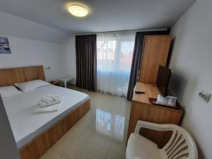 Un dormitorio con una cama y una silla y un televisor. en Casa Benny, en Costinesti