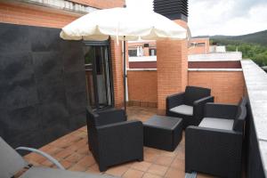 un patio con 2 sillas y una sombrilla en Dúplex con soleada terraza!, en Renedo de Piélagos