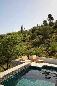a swimming pool with two lounge chairs next to a hill at Vanua house in Galatas