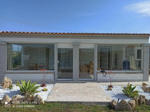 a house with large glass windows and a patio at Bello Bello Rooms in Santa Teresa Gallura