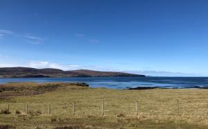 a field with a fence in front of a body of water at Coral Cabins in Dunvegan