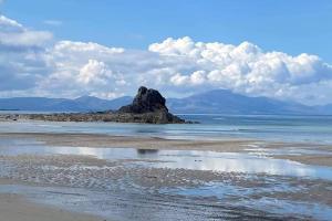 a rock in the water on a beach with mountains at Apartment on the Wild Atlantic Way in Tralee