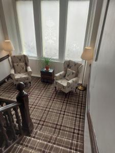 a living room with two chairs and two windows at The Ben Sheann in Strathyre