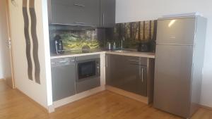 a kitchen with stainless steel appliances and a refrigerator at Ferienwohnung mit extra Schlafzimmer und Blick in den Bayrischen Wald oberhalb von Sankt Engelmar in Sankt Englmar