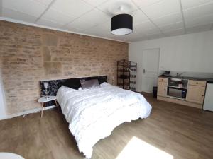a bedroom with a large bed and a brick wall at Appartement Jarnioux - Les Meublés des Pierres Dorées in Theizé