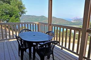 a blue table and chairs on a deck with a view at Camping Torraccia in Cargèse