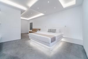 a white bedroom with a bed and a chair at Cape Sisu Suites in Akrotiri