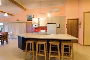 a kitchen with a island with bar stools at ARTHUR RIVER LODGE UPSTREAM in Arthur River