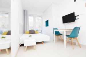 a white living room with a bed and a desk and chairs at Blue River - Pulaskiego B - private Apartment in Wrocław
