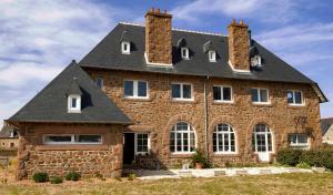 a large brick house with a roof at Le Presbytère du Talbert in Pleubian