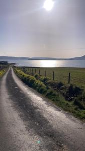 a dirt road next to a field and a body of water at Broadhaven Bay View Private House in Belmullet