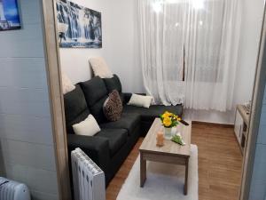 - un salon avec un canapé noir et une table dans l'établissement Apartamento playa, à La Corogne