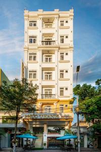 un edificio blanco alto con sombrillas delante en Phuc Thanh Luxury Hotel by THG, en Da Nang