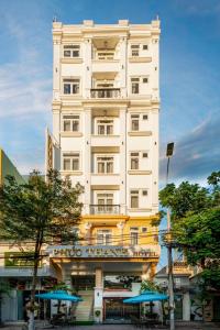 a tall white building with umbrellas in front of it at Phuc Thanh Luxury Hotel by THG in Danang