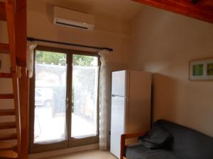 Habitación con nevera y puerta corredera de cristal en Maison T3 climatisée à barcares village en Le Barcarès