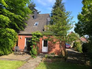 een rood bakstenen huis met een hek in de tuin bij Haus am Reithmoor in Großefehn 