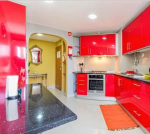 une cuisine avec des placards rouges et un comptoir noir dans l'établissement T3 Alex,moderno iluminado e amplo,excelente local, à Portimão