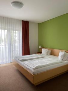 1 dormitorio con 1 cama grande y pared verde en Pension Schmidt, en Podersdorf am See