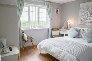 a bedroom with a white bed and a desk and window at Tregaddra Farm B&B in Helston