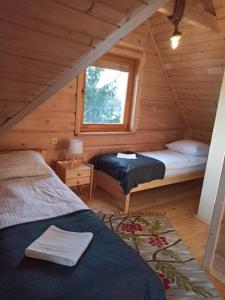 a bedroom with two beds in a wooden cabin at Domek 'Słoneczna 2' z RUSKĄ BANIĄ in Kluszkowce