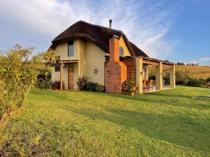 a house with a thatched roof on a grass field at Far Away Place in Curryʼs Post