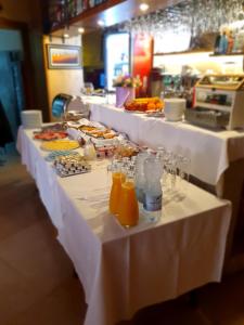 a buffet line with white tables with food and orange juice at Boutique Hotel Melissa in Poreč