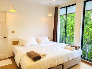 a bedroom with a large white bed with windows at KingsWay Thoddoo Maldives in Thoddoo