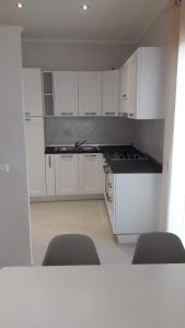 a kitchen with white cabinets and a sink and two chairs at La casa di Pier in Olbia