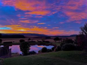 una puesta de sol sobre un estanque en un campo en Far Away Place, en Curryʼs Post