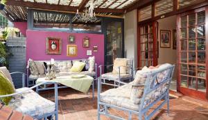 een patio met stoelen en een tafel en een paarse muur bij Tamarisk Bed & Breakfast in Durban